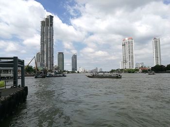 Tower bridge over river by buildings against sky