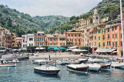 Sailboats moored on sea by buildings in city