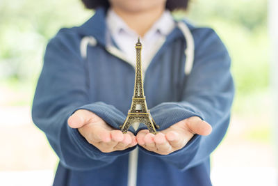 Midsection of woman holding artificial eiffel tower