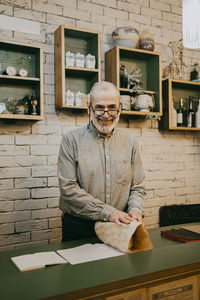 Portrait of smiling senior male owner wrapping box at home decor store