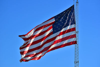 Low angle view of flag against clear blue sky