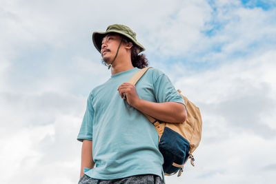 Low angle view of young woman standing against sky