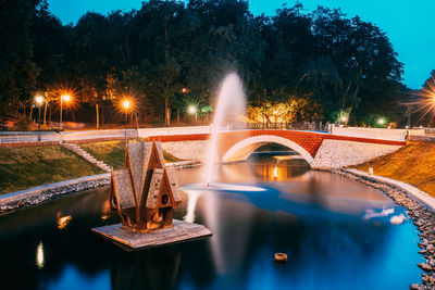 Illuminated arch bridge over lake at night