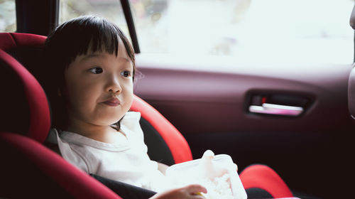 Cute girl eating food while sitting in car