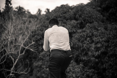 Rear view of man walking against trees