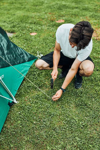 Young man putting up a tent on camping during summer vacation trip. teenager putting the stakes