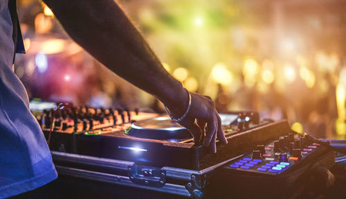 Cropped hand of dj playing music at nightclub