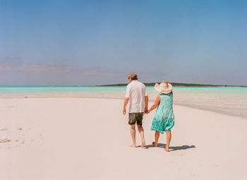 Couple walking at beach against sky