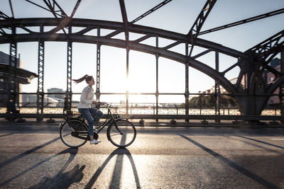 Young cyclist on a bridge at sunset