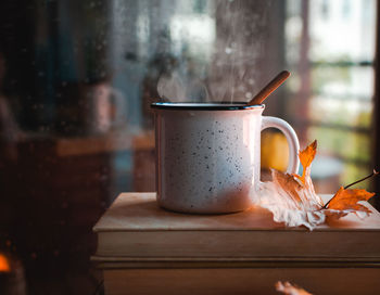 Stacked books and hot tea against rainy window