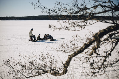 Fathers with sons ice fishing on sunny day in winter