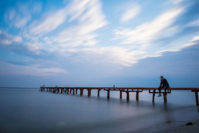 Silhouette man standing on pier over sea against sky