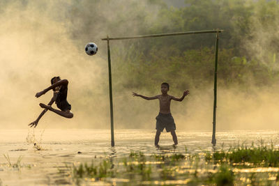 Boys playing soccer playing on rainy season