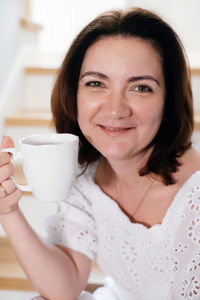 Portrait of young woman holding coffee