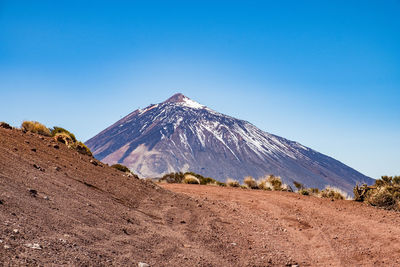 Scenic view of snowcapped mountains against clear blue sky