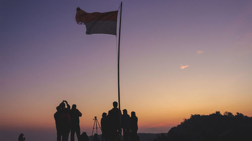 Silhouette people photographing against sky during sunset