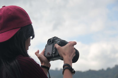 Midsection of woman photographing with camera against sky