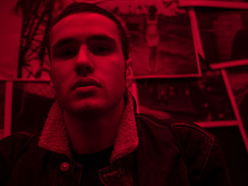 Close-up portrait of young man sitting in darkroom