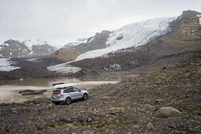 Car driving on gravel road near montain glacier