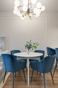 Dining table with blue chairs and large chandelier in the interior