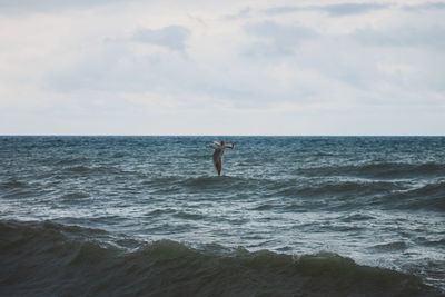 Man surfing in sea against sky