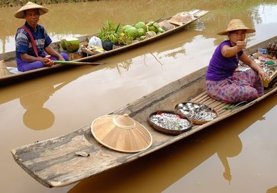 Vendors sitting on boats in river at floating market