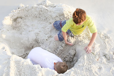 High angle view of boy playing on sand at beach