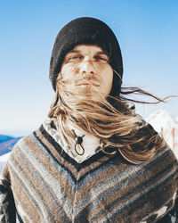 Man with poncho and knit hat on sunny day