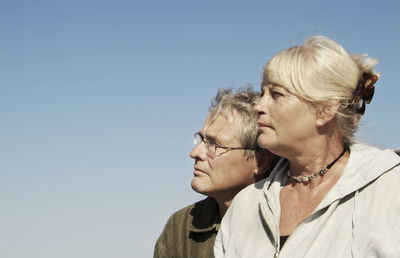 Thoughtful senior couple looking away against clear sky