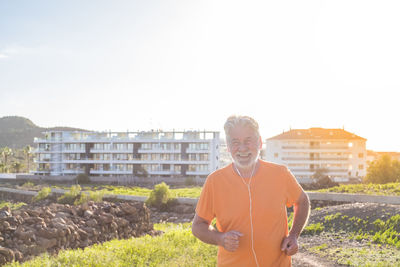 Portrait of smiling man standing against buildings in city