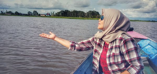 Side view of man on lake against sky
