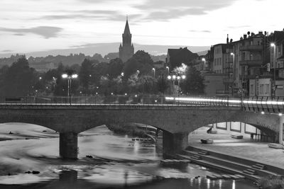 Arch bridge over river amidst buildings in city