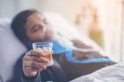 Midsection of man drinking glass on bed