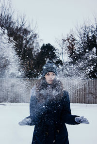 Photo in defocus. young attractive girl throwing snow with her arms. closeup shot.