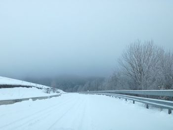 Snow covered road against clear sky