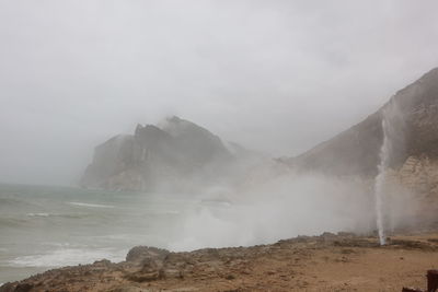 Geyser at seaside against sky