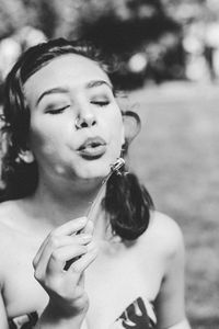 Close-up of young woman blowing dandelion