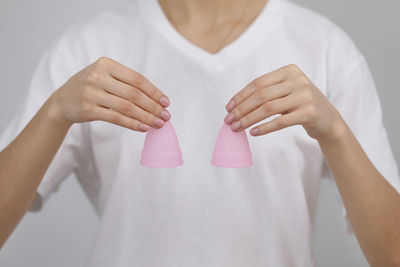 Midsection of woman holding hands over white background