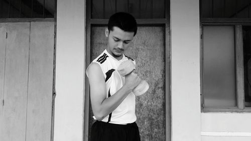 Full length of young man standing against building