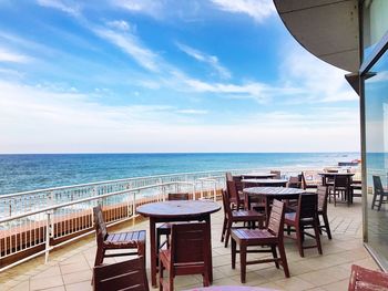 Chairs and table at beach against sky