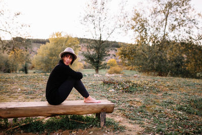 Full length of woman sitting on bench at park