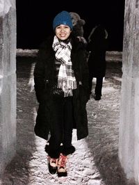 Full length portrait of smiling woman standing in snow