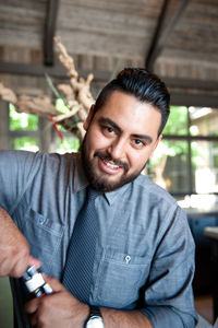 Portrait of bartender opening bottle in bar