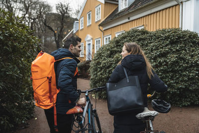 Smiling couple walking with bicycle at back yard