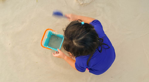 High angle view of child holding sand on beach