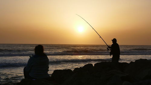 Silhouette of people on beach at sunset