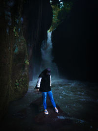 Rear view of boy standing on rock in forest