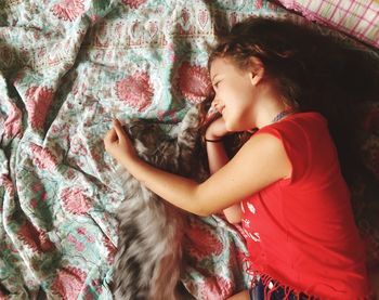 High angle view of smiling girl with cat lying on bed at home