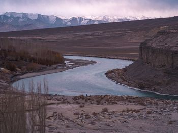 Scenic view of river by mountains against sky