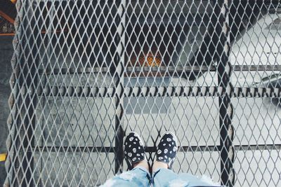 Low section of person standing on chainlink fence